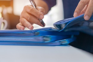 hand signing document in blue folder | year end closing checklist