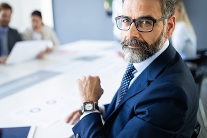 bearded mature man in suit looking at camera with blurred background | HOA financial management