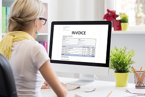 woman in office with sample invoice document on computer | HOA invoice processing