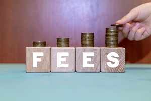 hand putting coin on growing coins stack on wooden blocks with fees word | how often do hoa fees increase