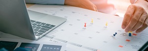 man with laptop putting pins on calendar | type of HOA management