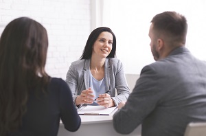 woman talking to young couple at personal meeting in office | self-manage a community association