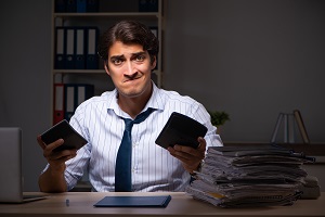 financial manager working late at night in office with unpleasant facial expression | bank statements of an HOA