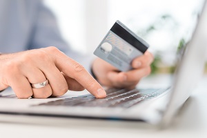 hands holding credit card and using laptop | hoa online payments