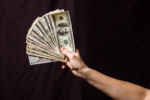 hands holding a fan of dollars on a black background | modified accrual basis of accounting