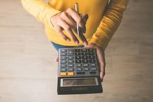 woman using a calculator with a pen in her hand | average hoa fees
