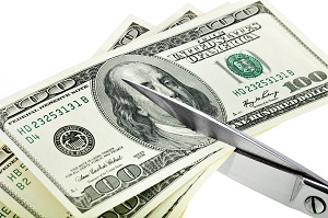 cutting dollars with scissors on a white background | budgetting for winter in an HOA