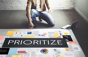 man analyzing documents on the floor with word 'prioritize' in white font and black background | community association budget management