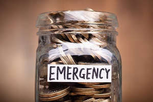 coins in jar with emergency label over wooden desk | what are hoa fees used for